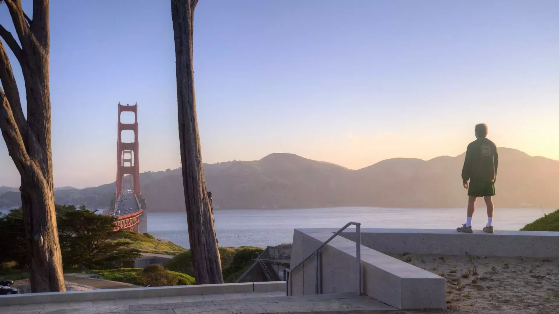 Un homme surplombe le Golden Gate Bridge avec des montagnes en arrière-plan.